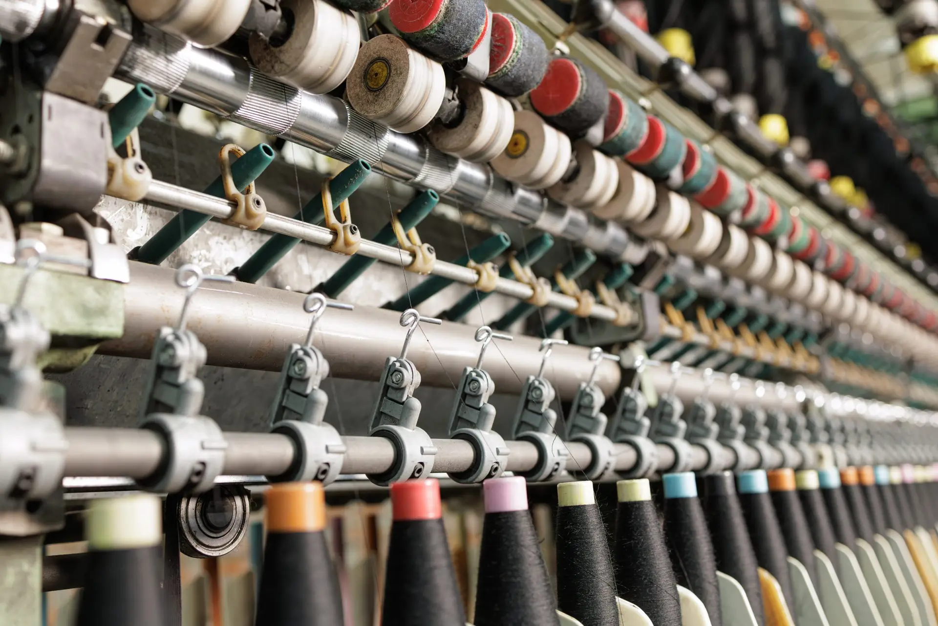 Closeup textile loom machine with yarn spools and feeding mechanism